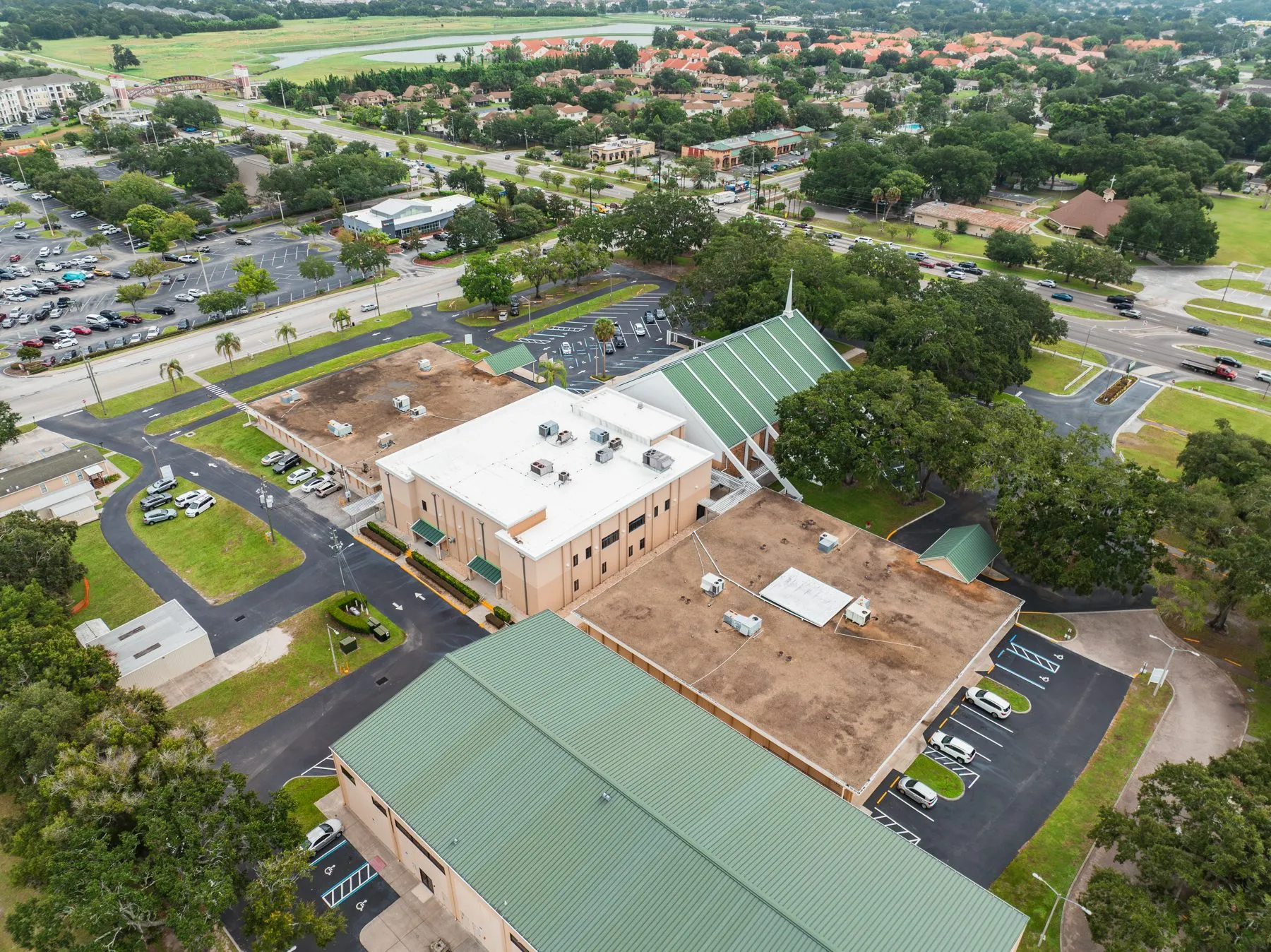 Aerial view of a Florida church campus with a new white flat roof and green metal roofs