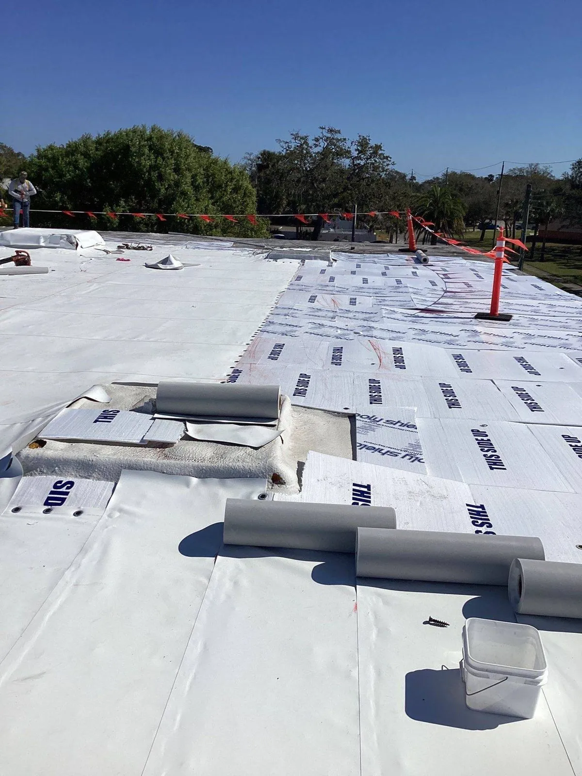 Prefabricated Duro-Last deck sheet being unrolled on a commercial roof
